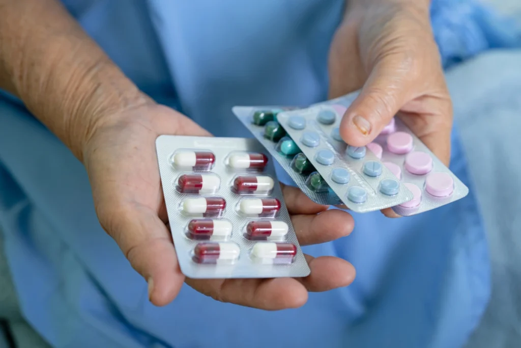 Person holding blister packs of anti-inflammatory medications in hand.