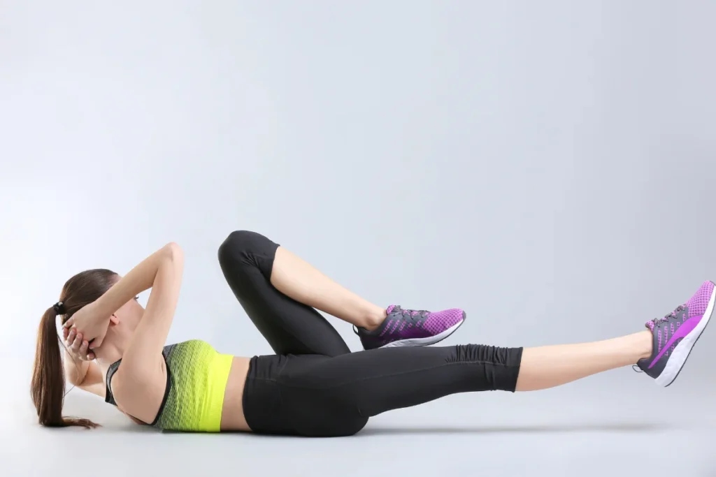 A woman performing bicycle crunches as part of her routine for exercises to lose belly fat at home, targeting core muscles.