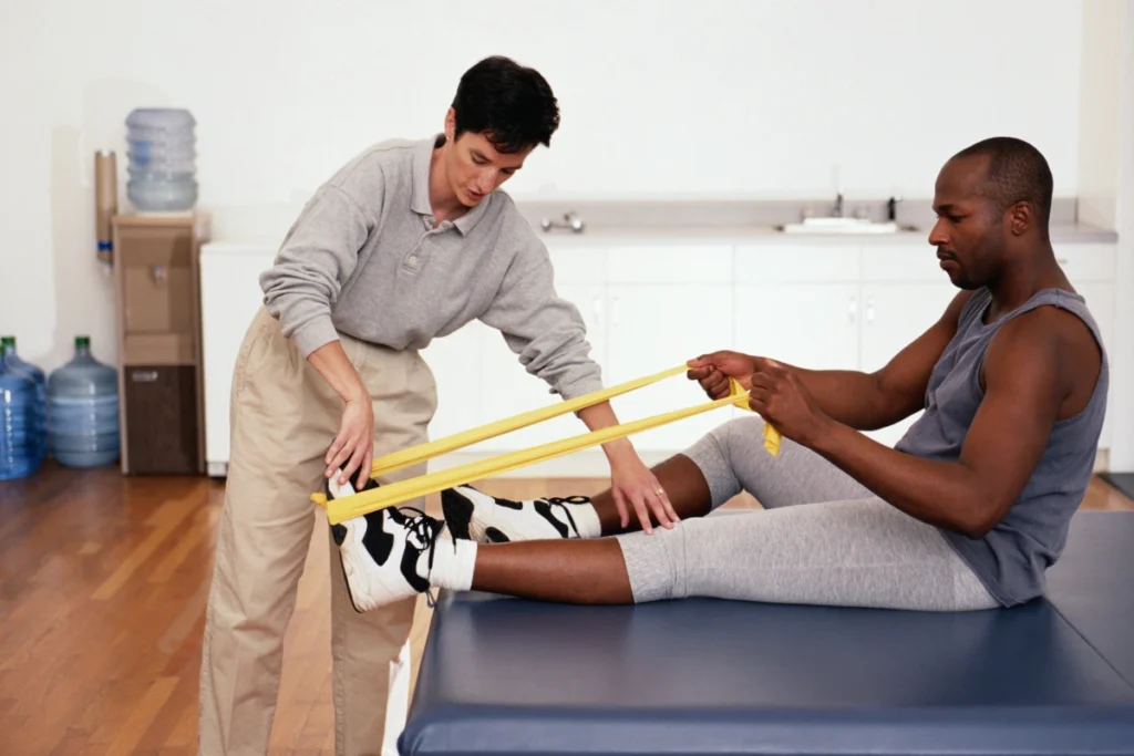 A physical therapist helps a patient with resistance band exercises to improve strength and mobility during a rehabilitation session. The image highlights targeted therapy.