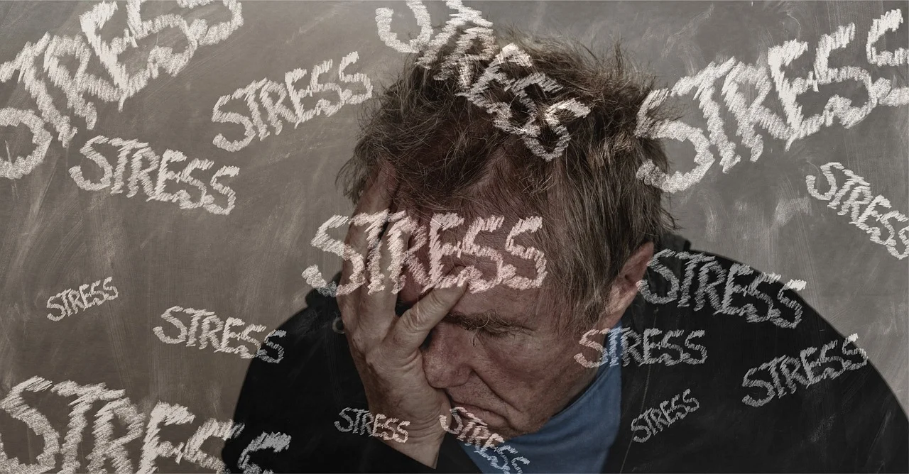 A stressed man holding his head in his hand, surrounded by the word 'STRESS' repeatedly written, representing the overwhelming feeling of stress and anxiety.