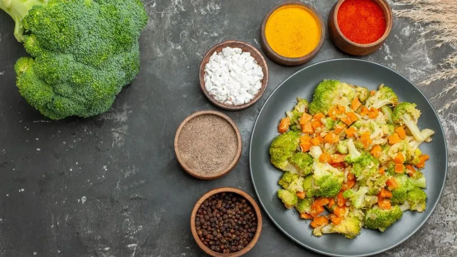 High Protein Low Carb Vegetarian Meals featuring broccoli and carrots with various seasonings on a black plate, offering a nutritious, balanced vegetarian option.