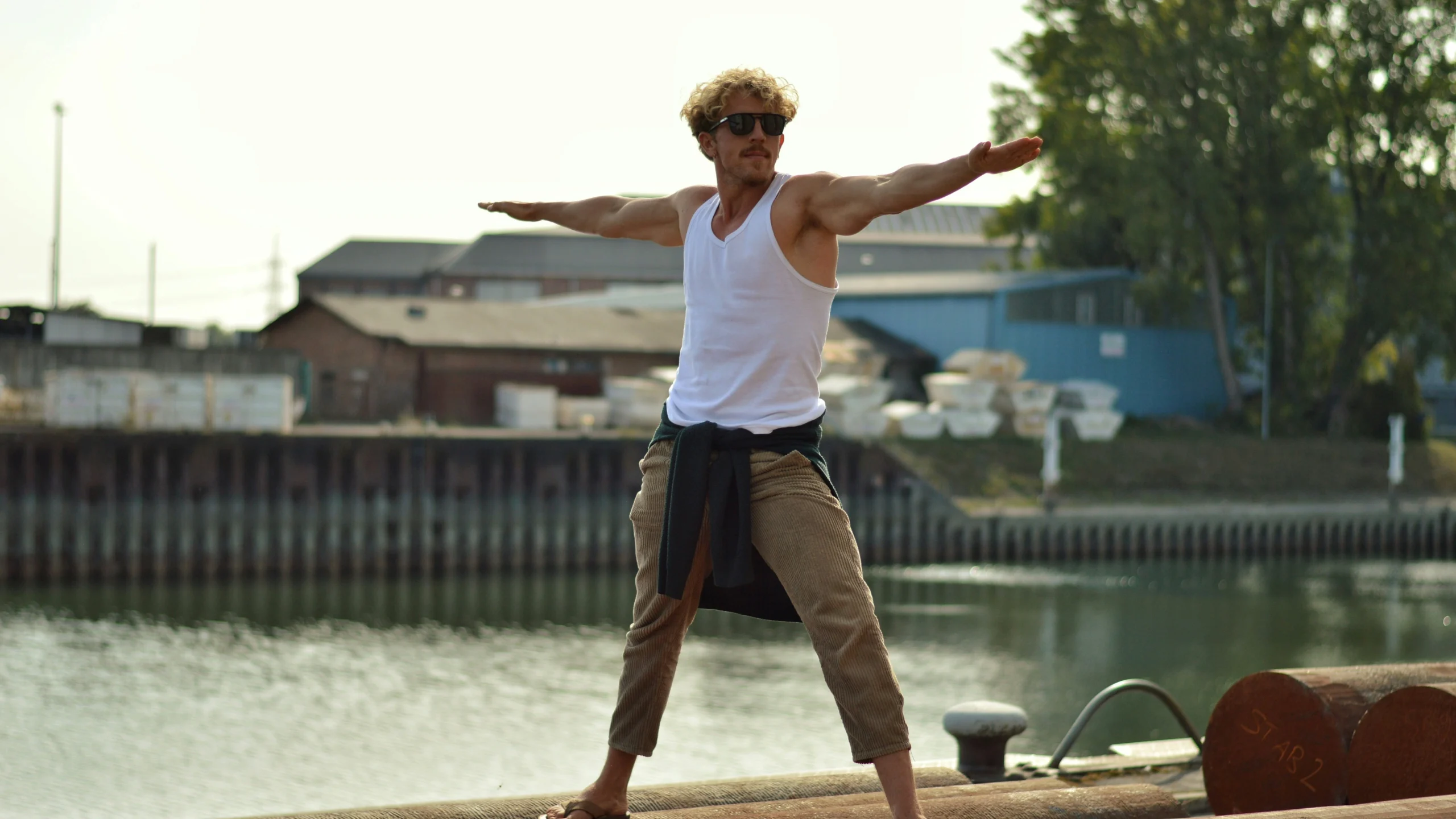 Man practicing Warrior Pose near a serene waterfront, highlighting the benefits of yoga for men, including improved strength, flexibility, and mindfulness.