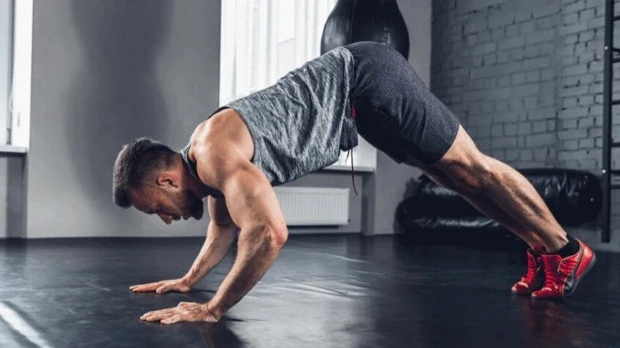 A man performing a pike push-up, one of the best bodyweight shoulder exercises, focusing on building shoulder strength and mobility in a home gym setting.