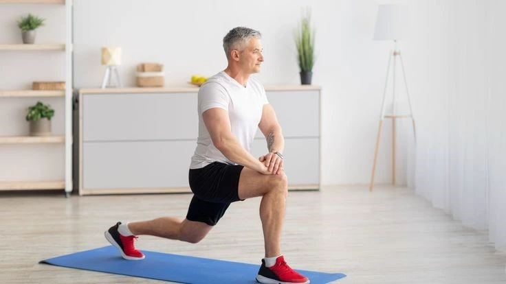 Middle-aged man performing a lunge on a yoga mat in a bright room. Best Bodyweight Exercises for Weight Loss to improve strength, flexibility, and endurance.