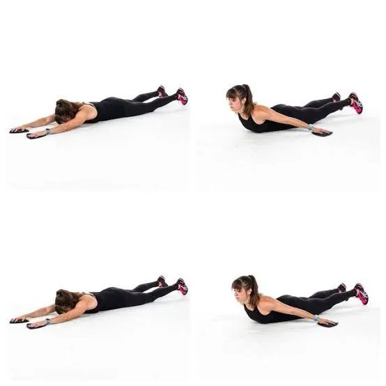 Person performing Reverse Snow Angels, a bodyweight exercises for back strength, lying face down with arms moving in arcs.