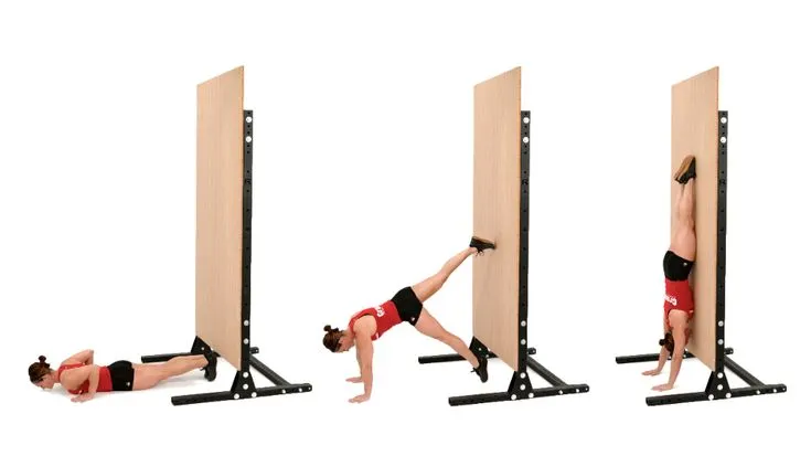 Person performing Wall Walks, a bodyweight exercise for back strength, walking feet up the wall from plank to handstand position.