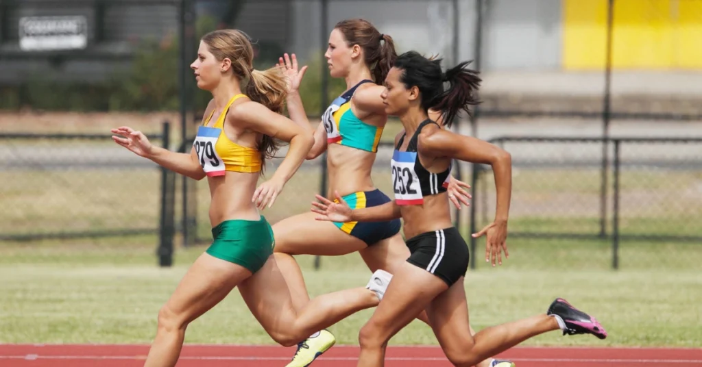 Female athletes sprinting during a race, showcasing improved athletic performance and strength from consistent strength training exercises.