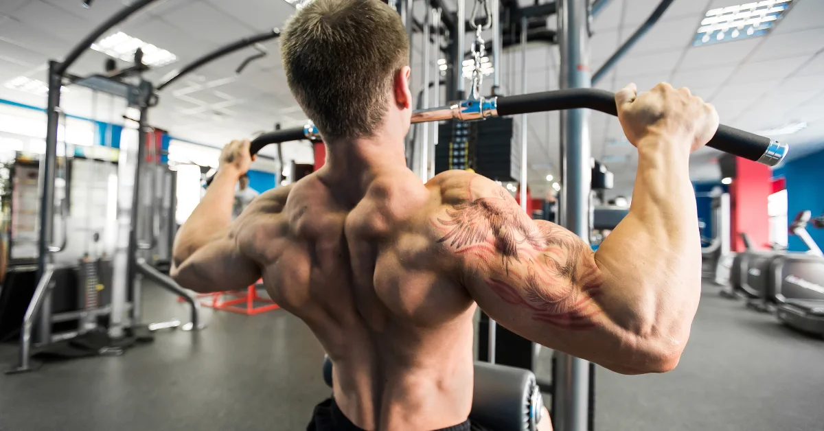 A muscular man performing the Cable Pullover Exercise for Lats on a cable machine to build back width and definition in a gym setting.