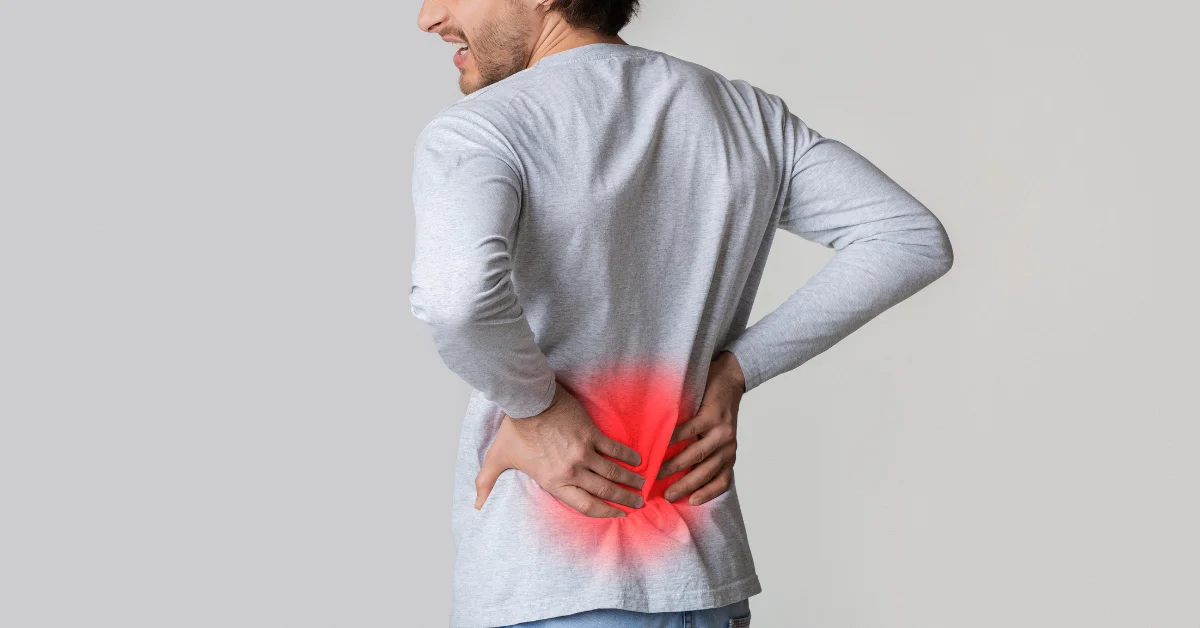 Man experiencing discomfort and holding his lower back, illustrating the need for the 15 best lower back stretches to relieve pain and boost flexibility.