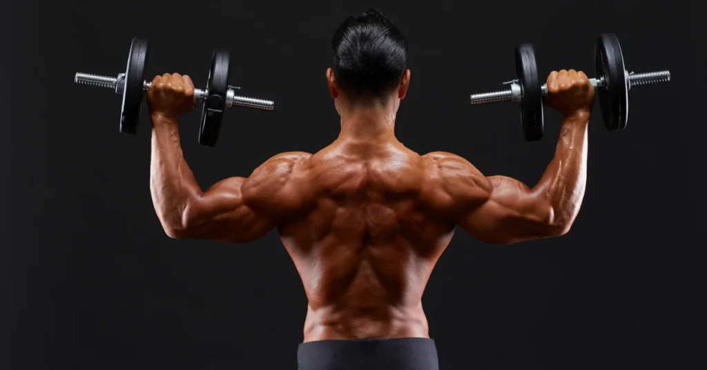 Man performing Standing Dumbbell Military Press showcasing muscular back and proper overhead lifting form for shoulder strength development.